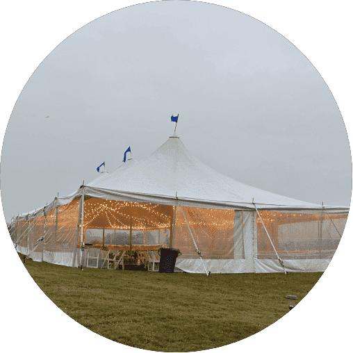 Elegant sailcloth tent with decorative lighting, set on grass, showcasing a spacious interior for events, reflecting Prime Tent & Furniture Rental's premium offerings.