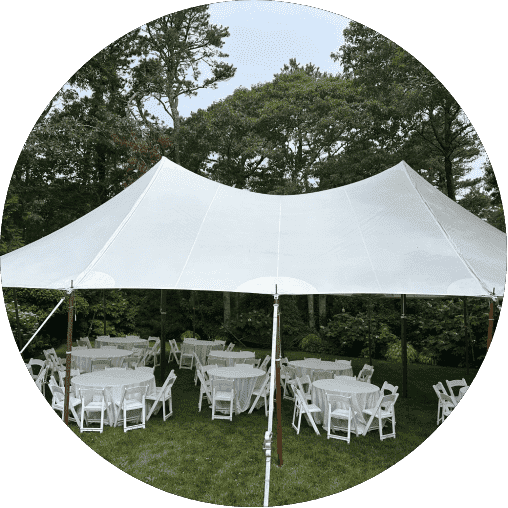 White tent set up for an outdoor event, featuring round tables with white tablecloths and chairs, surrounded by greenery, highlighting Prime Tent & Furniture Rental's event rental offerings.